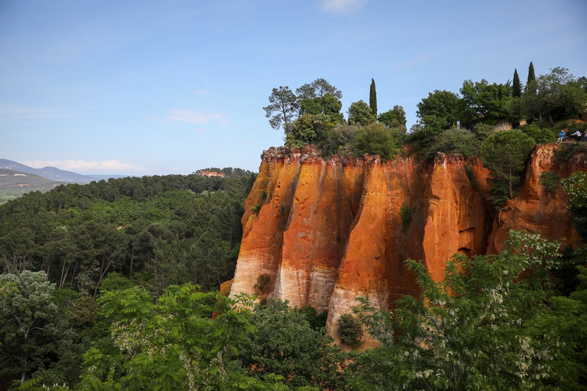 Orange ochre cliffs surrounded by green forest in Roussillon, Provence